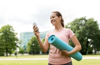 fitness, sport and healthy lifestyle concept - happy smiling woman with exercise mat and smartphone at park. woman with exercise mat and smartphone at park
