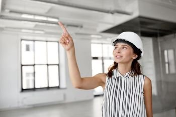 building, architecture and construction business concept - businesswoman or architect in helmet at office room. architect in helmet at office room