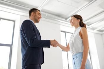 business people, partnership and cooperation concept - happy smiling businesswoman and businessman shaking hands at office. businesswoman and businessman shaking hands