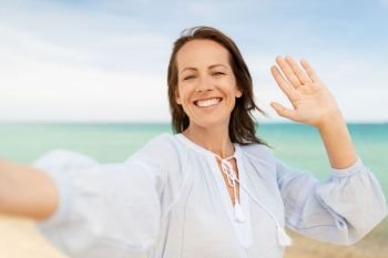summer holidays and leisure concept - happy smiling woman taking selfie on beach. happy smiling woman taking selfie on summer beach