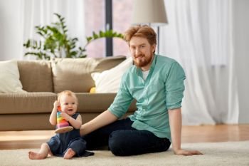 family, fatherhood and people concept - happy red haired father with ball playing with little baby daughter at home. father playing with little baby daughter at home