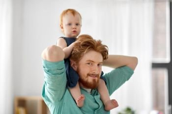 family, fatherhood and people concept - happy red haired father carrying his little baby daughter on neck at home. father carrying his little baby daughter on neck
