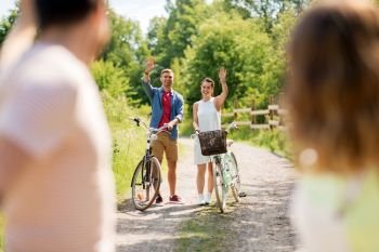 people, leisure and lifestyle concept - happy young friends with fixed gear bicycles in summer waving hands. happy friends with fixed gear bicycles in summer