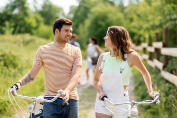 people, leisure and lifestyle concept - happy young couple with fixed gear bicycles on country road in summer. happy couple with fixed gear bicycles in summer