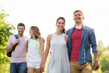 travel, tourism, hike and friendship concept - group of smiling friends walking with backpack in summer. group of smiling friends with backpack hiking
