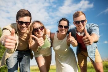 leisure, people and friendship concept - happy teenage friends having fun outdoors in summer showing thumbs up. happy teenage friends showing thumbs up in summer