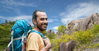 adventure, travel, tourism, hike and people concept - smiling man with backpack over background of seychelles island. smiling man with backpack over seychelles