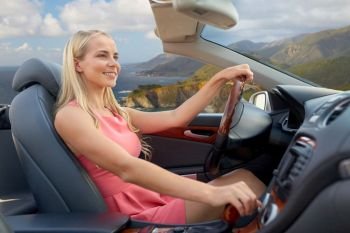 travel, road trip and people concept - happy young woman driving convertible car over bixby creek bridge on big sur coast of california background. woman driving convertible car on big sur coast