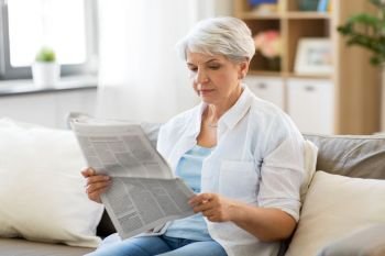 age and people concept - senior woman reading newspaper at home. senior woman reading newspaper at home
