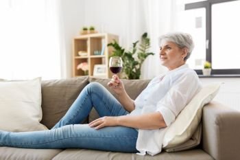 people, alcohol and leisure concept - senior woman with glass of red wine at home. senior woman with glass of red wine at home