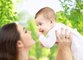 family and motherhood concept - happy smiling young mother with little baby over green natural background. mother with baby over green natural background