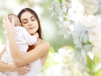 family and motherhood concept - happy young mother holding little baby over cherry blossom background. mother with baby over cherry blossom background