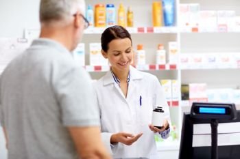 medicine, pharmaceutics, healthcare and people concept - apothecary showing drug to senior male customer at drugstore. apothecary and senior customer at pharmacy