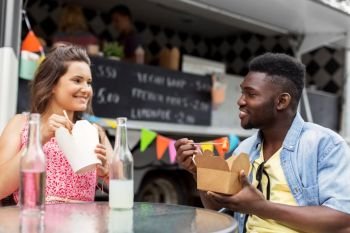 leisure and people concept - happy mixed race couple eating and talking at food truck. mixed race couple eating and talking at food truck
