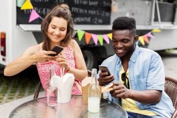 leisure, technology and people concept - happy mixed race couple photographing wok by smartphones at food truck. mixed race couple photographing wok at food truck