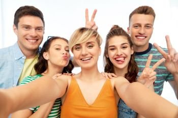 friendship and people concept - group of happy smiling friends taking selfie and showing peace hand sign over white background. happy friends taking selfie and showing peace