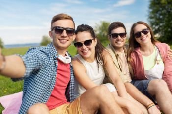 leisure, people and friendship concept - happy teenage friends taking selfie outdoors in summer. happy friends taking selfie outdoors in summer