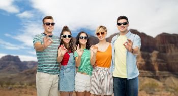 travel, tourism and summer holidays concept - group of happy smiling friends in sunglasses showing ok hand sign over grand canyon national park background. friends in sunglasses showing ok over grand canyon