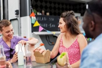 leisure and people concept - happy friends with non alcoholic drinks eating and talking at food truck. happy friends eating at food truck