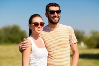people and relationships concept - happy couple in sunglasses outdoors in summer. happy couple in sunglasses outdoors in summer