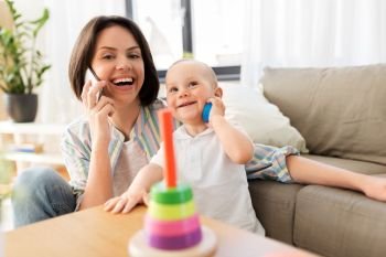 family, child and motherhood concept - happy mother calling on smartphone and little baby boy playing developmental toy at home. mother calling phone and baby boy playing at home
