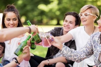 leisure, people and celebration concept - happy friends clinking non alcoholic drinks at summer park. happy friends clinking drinks at summer park