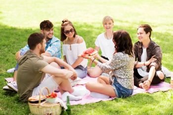 friendship, leisure and summer concept - group of happy friends eating watermelon at picnic in park. happy friends eating watermelon at summer picnic