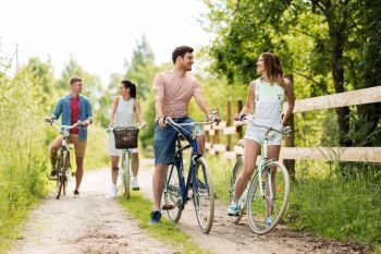 people, leisure and lifestyle concept - happy young friends with fixed gear bicycles on road in summer. happy friends with fixed gear bicycles in summer