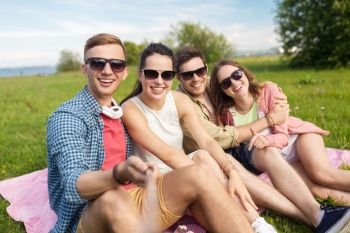 friendship, leisure and technology concept - group of happy smiling friends taking picture by selfie stick outdoors in summer. friends taking picture by selfie stick in summer