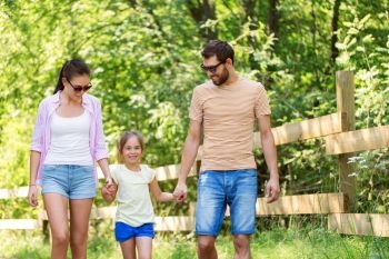 family, leisure and people concept - happy mother, father and little daughter walking in summer park. happy family walking in summer park