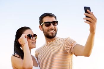 technology and people concept - happy couple taking selfie by smartphone in summer. happy couple taking selfie by smartphone in summer
