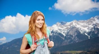 adventure, travel, tourism, hike and people concept - smiling young woman with backpack over alps mountains background. smiling woman with backpack over alps mountains