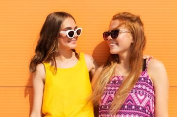 fashion, leisure and people concept - smiling teenage girls in summer clothes hugging outdoors. teenage girls in summer clothes hugging outdoors