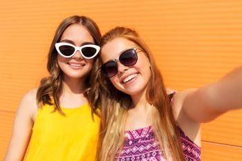 fashion, leisure and people concept - smiling teenage girls taking selfie outdoors in summer. teenage girls taking selfie outdoors in summer