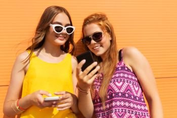 technology, leisure and people concept - happy smiling teenage girls in summer clothes with smartphones outdoors. teenage girls with smartphones in summer outdoors