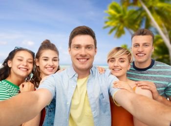 travel, tourism and summer holidays concept - group of happy smiling friends taking selfie over tropical beach background in french polynesia. happy friends taking selfie over white background