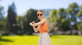 sport, leisure and people concept - smiling teenage girl with racket playing tennis over summer park background. happy teenage girl with racket playing tennis