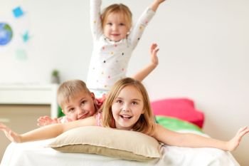 childhood, leisure and family concept - happy little kids having fun in bed at home. happy little kids having fun in bed at home