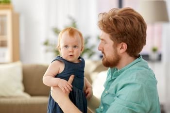 family, fatherhood and people concept - happy red haired father with little baby daughter at home. happy father with little baby daughter at home