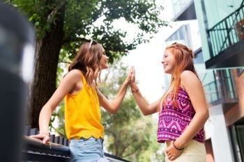 leisure, gesture and friendship concept - happy smiling teenage girls or friends talking on city street in summer. teenage girls or friends talking in summer city