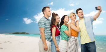 travel, technology and summer holidays concept - group of happy smiling friends taking selfie by smartphone over tropical beach background in french polynesia. friends taking selfie by smartphone over beach