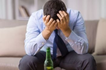 alcoholism, alcohol addiction and people concept - male alcoholic with bottle of beer at home. male alcoholic with bottle of beer at home