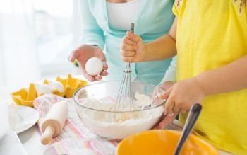 family, cooking, baking and people concept - close up of mother and little daughter with flour, eggs and whisk making dough at home kitchen. mother and daughter making dough at home kitchen