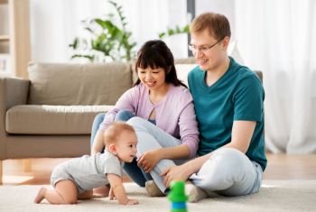 family, parenthood and people concept - happy mother and father with baby boy at home. happy family with baby boy at home