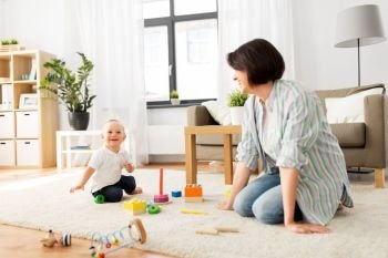 family, child and motherhood concept - happy mother with little baby boy playing developmental toys at home. happy mother with little baby boy playing at home