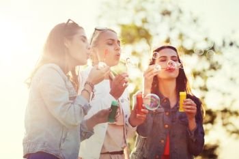 summer vacation, holidays, fun and people concept - group of happy young women or teenage girls blowing bubbles outdoors. young women or girls blowing bubbles outdoors