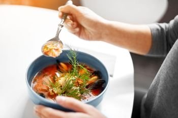 food, new nordic cuisine and people concept - woman eating seafood soup with fish and blue mussels at cafe or restaurant. woman eating seafood soup at restaurant