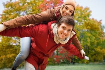 love, relationships, season and people concept - happy young couple having fun over autumn park background. happy young couple having fun in autumn park
