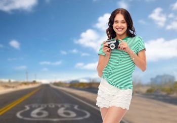 travel, tourism and photography concept - smiling teenage girl with vintage film camera over route 66 background. teenage girl with vintage film camera on route 66