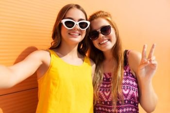 fashion, leisure and people concept - smiling teenage girls taking selfie and showing peace outdoors in summer. teenage girls taking selfie in summer